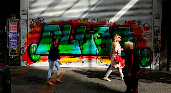 Personas caminando por la calle, de fondo unos grafitis