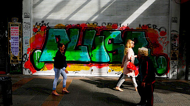 Personas caminando por la calle, de fondo unos grafitis