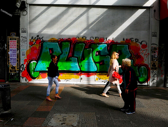 Personas caminando por la calle, de fondo unos grafitis