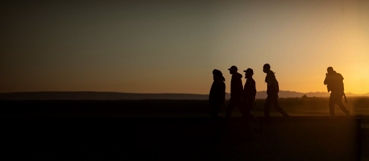 Personas caminando al atardecer en un territorio desértico