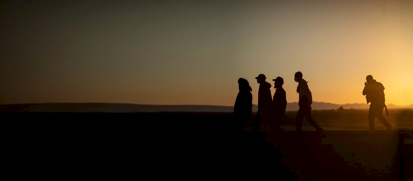 Migrantes caminando al atardecer