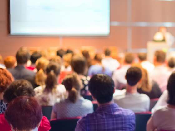 Audience attending a presentation during a professional conference or educational summit in a modern venue.