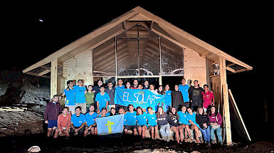 grupo de jóvenes frente a nueva capilla, fondo cielo de noche