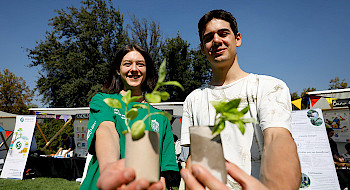 Dos jóvenes muestran unas plantas pequeñas.