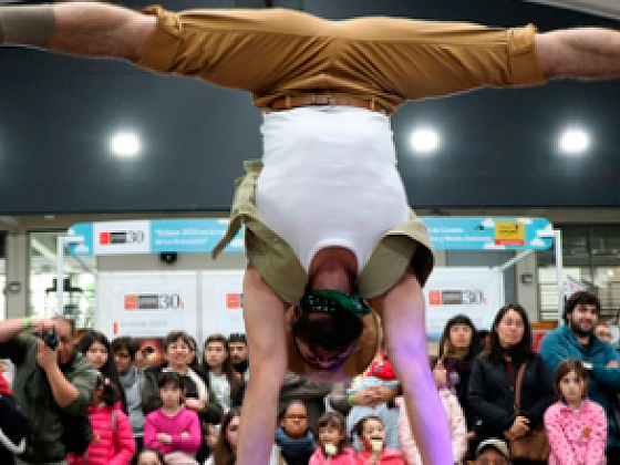 Una persona realizando una acrobacia en un escenario frente a un grupo de personas.